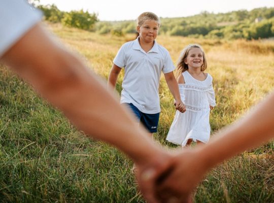 A couple of people holding hands in a field