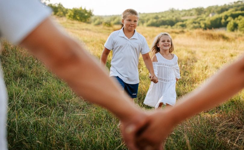A couple of people holding hands in a field